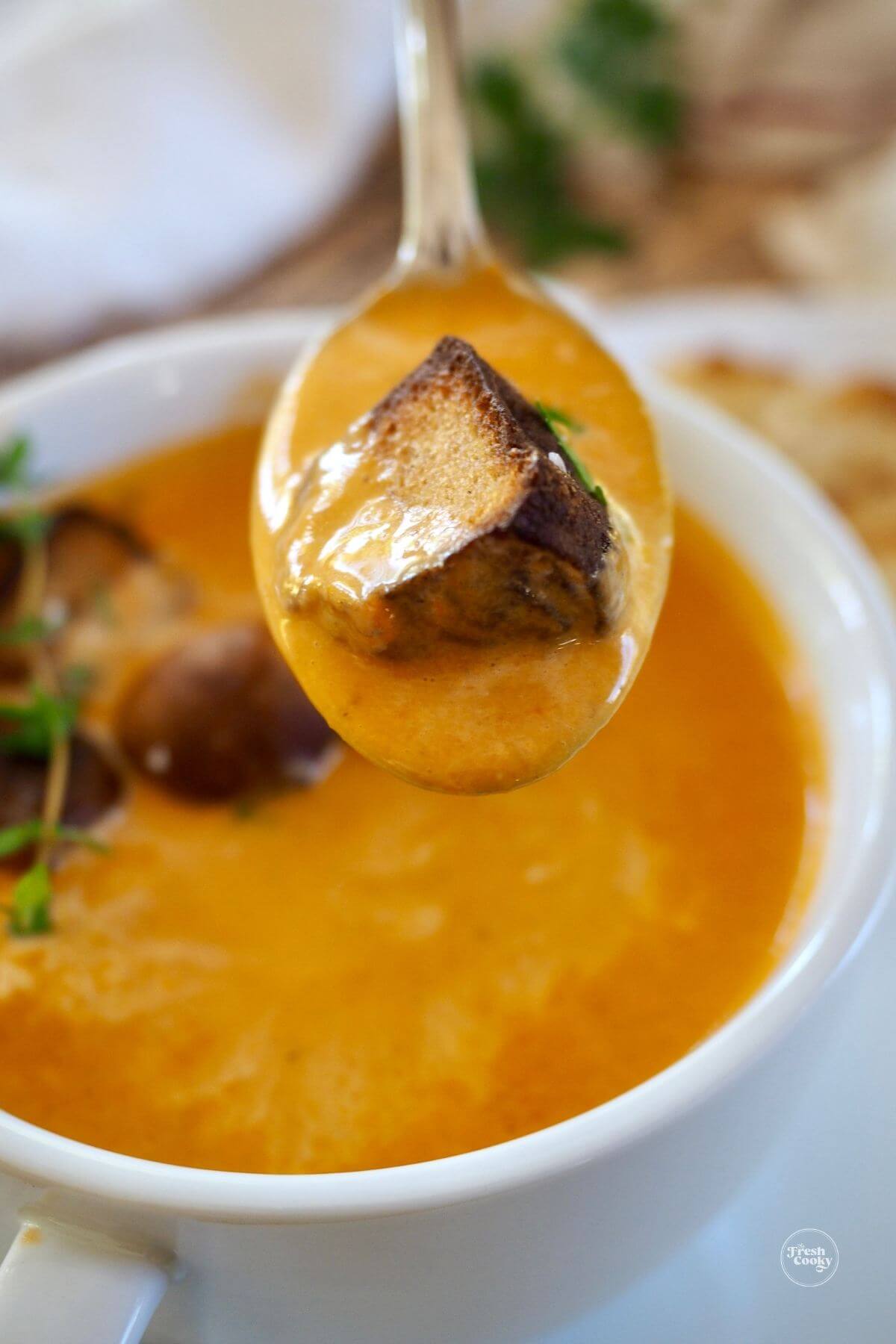 Spoonful of tomato bisque with crouton.
