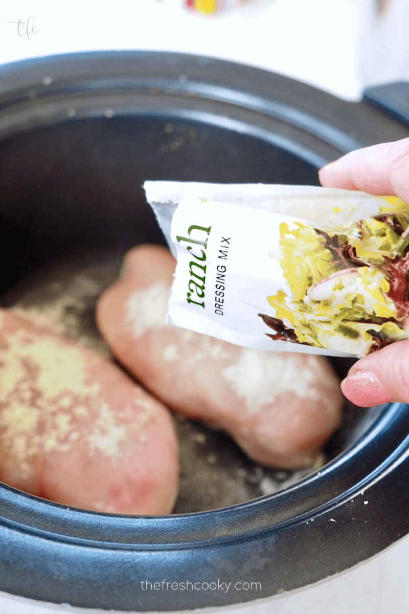 Adding ranch dressing mix on top of chicken breasts in crockpot ranch chicken.