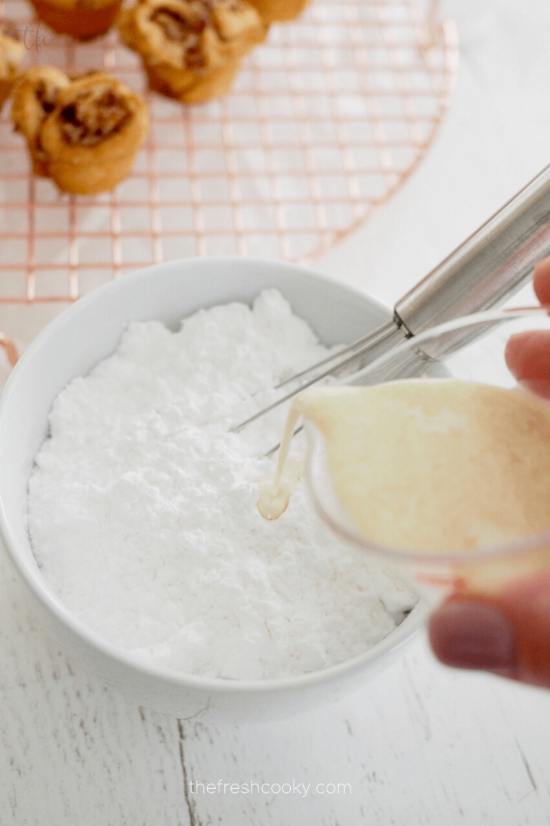 Pouring vanilla cream into powdered sugar for glaze for mini king cakes. 