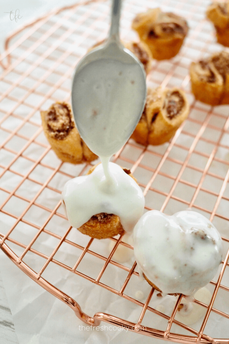 Drizzling glaze onto Mini King Cake Bites with crescent rolls.