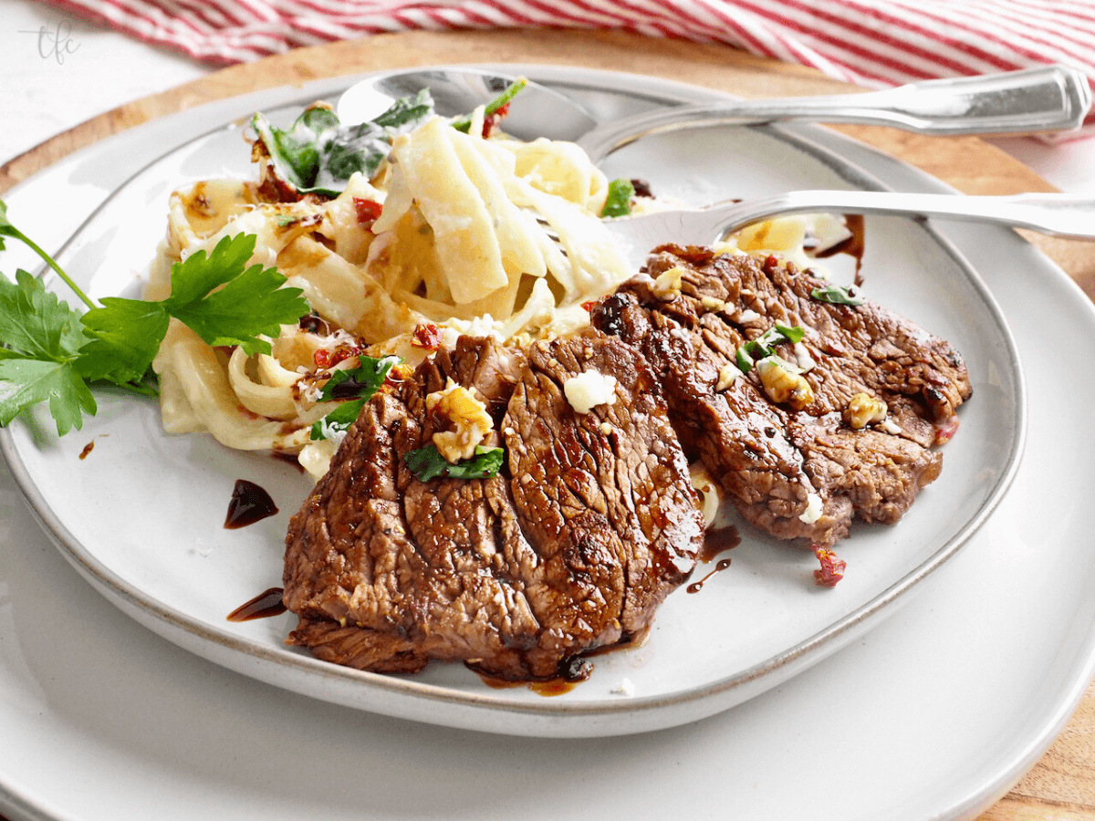 Olive Garden Steak Alfredo on a plate with a fork twirled in some fettuccine.