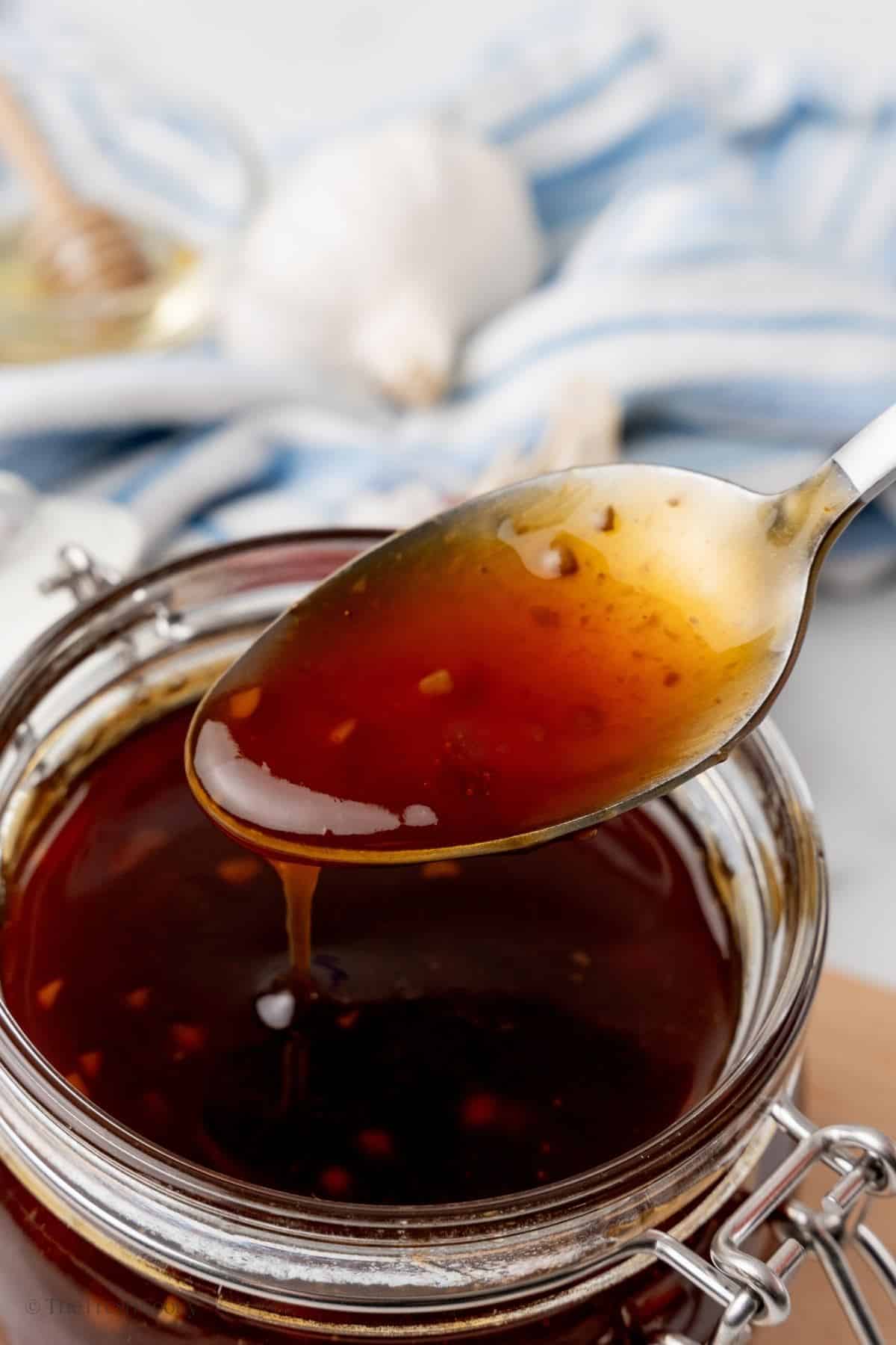 Spoonful of glossy teriyaki sauce in a jar. 