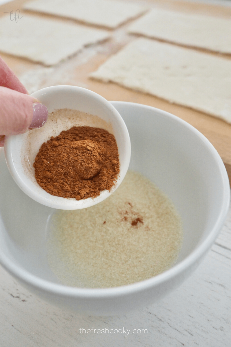 Mixing cinnamon and sugar together to spread onto crescent rolls for mini king cakes. 