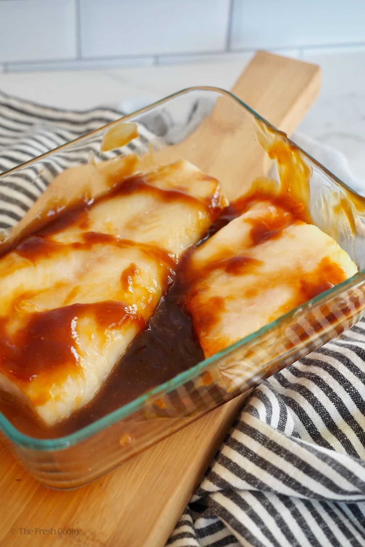 Fish marinating in teriyaki in a glass dish. 