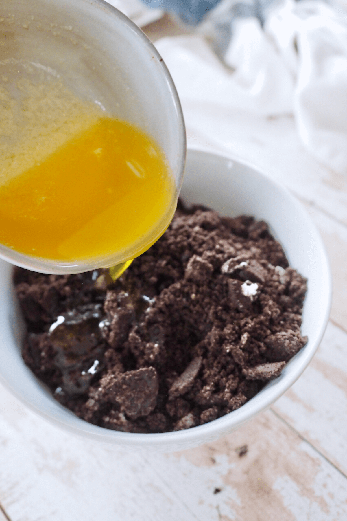 Pouring melted butter Oreo cookie crumbs. 