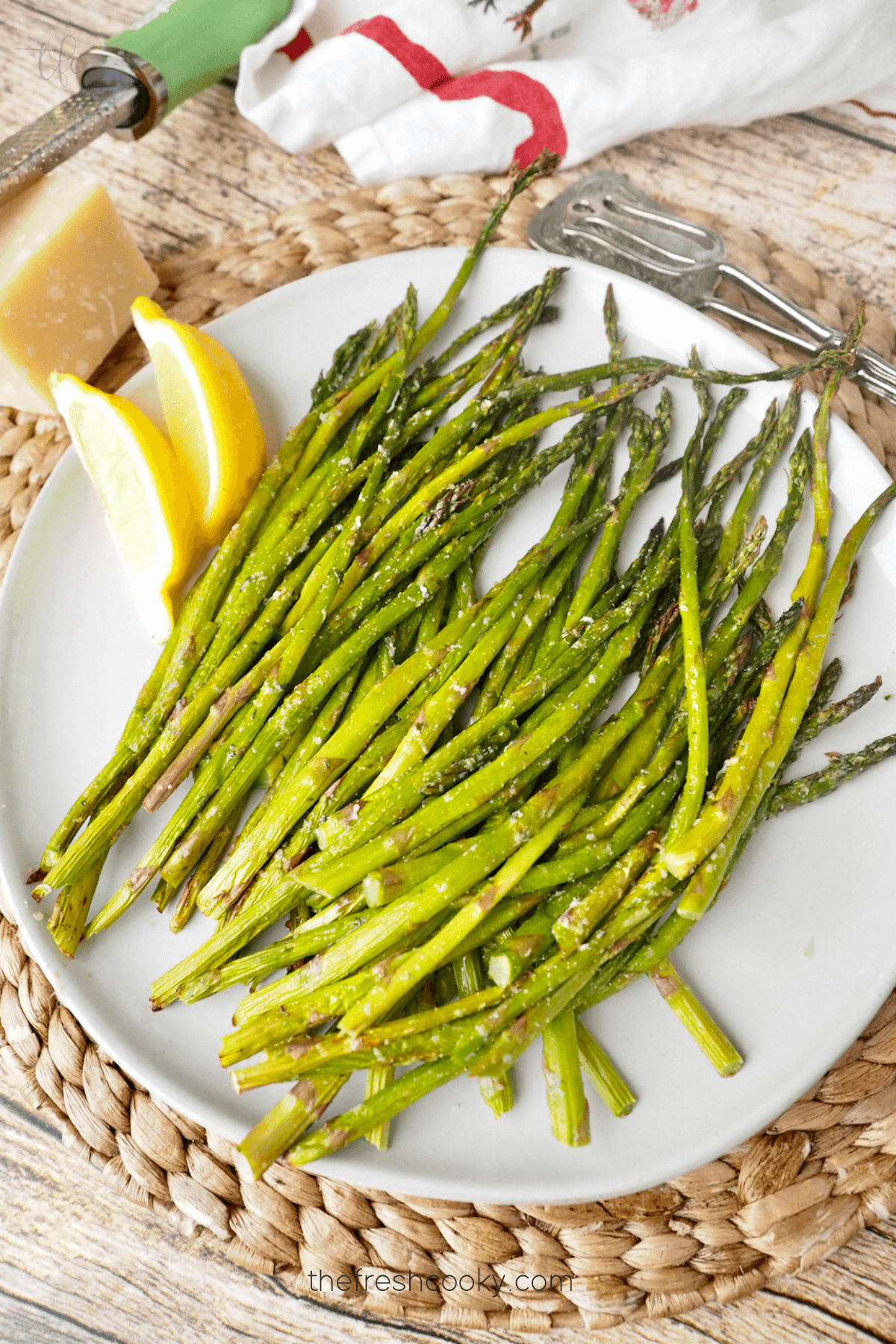 Top down shot of bright green air fryer asparagus with lemon wedges.