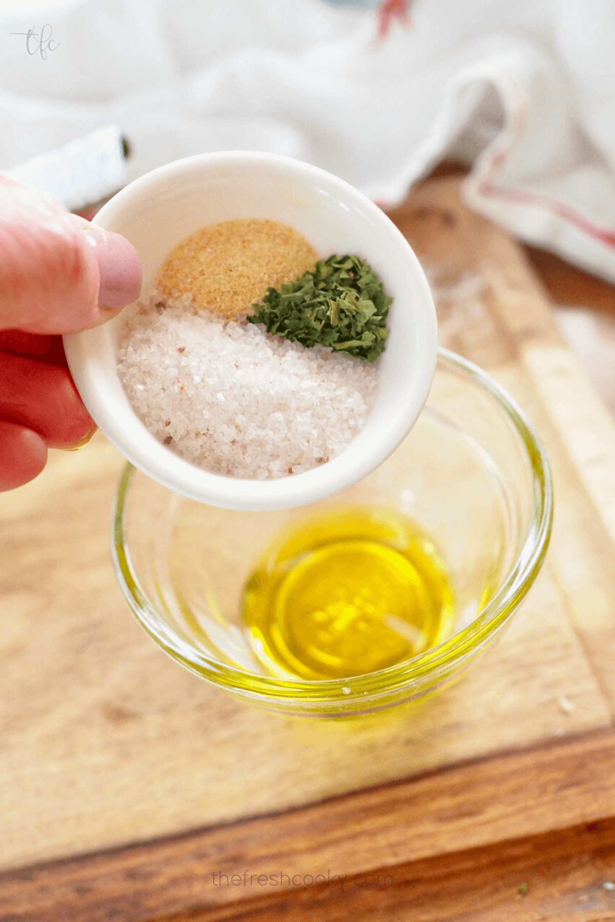 Handing pouring in spices into oil to make infusion for air fryer asparagus.