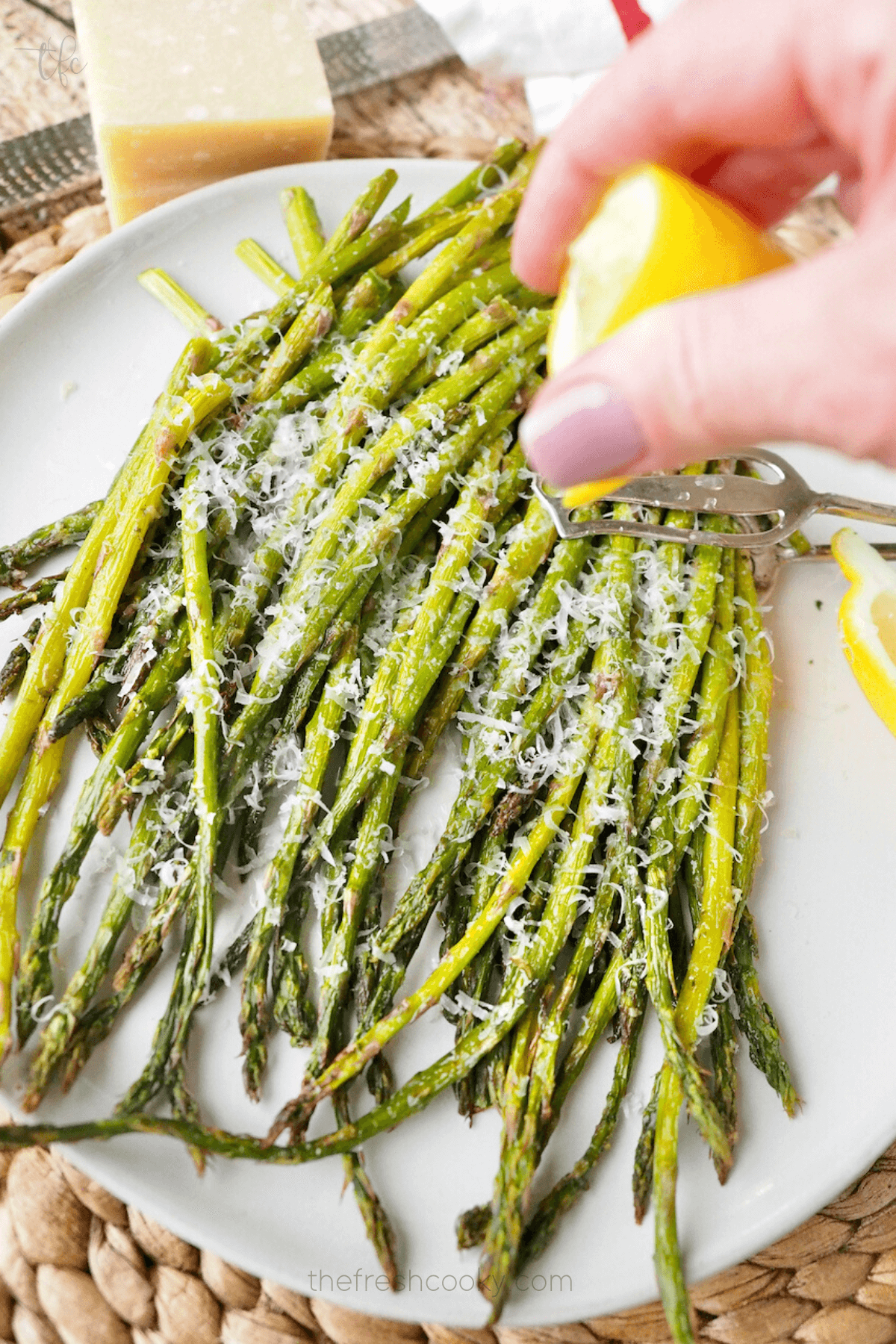 Squeezing on lemon juice onto Air fryer asparagus on a plate.