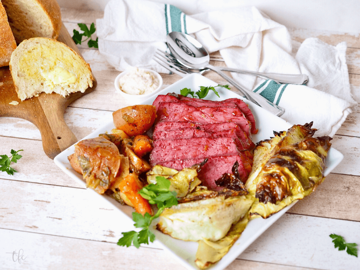 Baked corned beef and cabbage recipe the best on a platter with a wedge of soda bread in background.