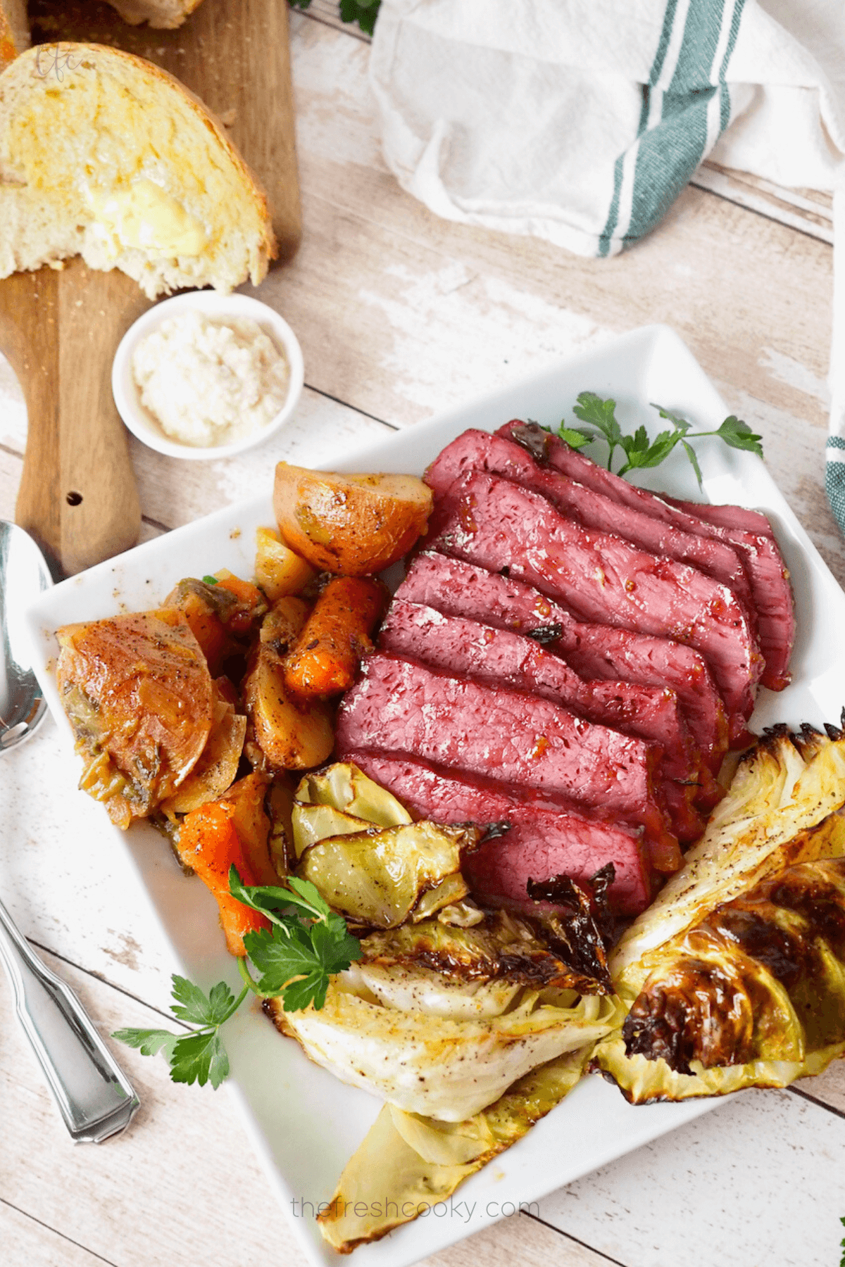 Easy and delicious baked corned beef recipe on platter with cabbage, potatoes and carrots. 