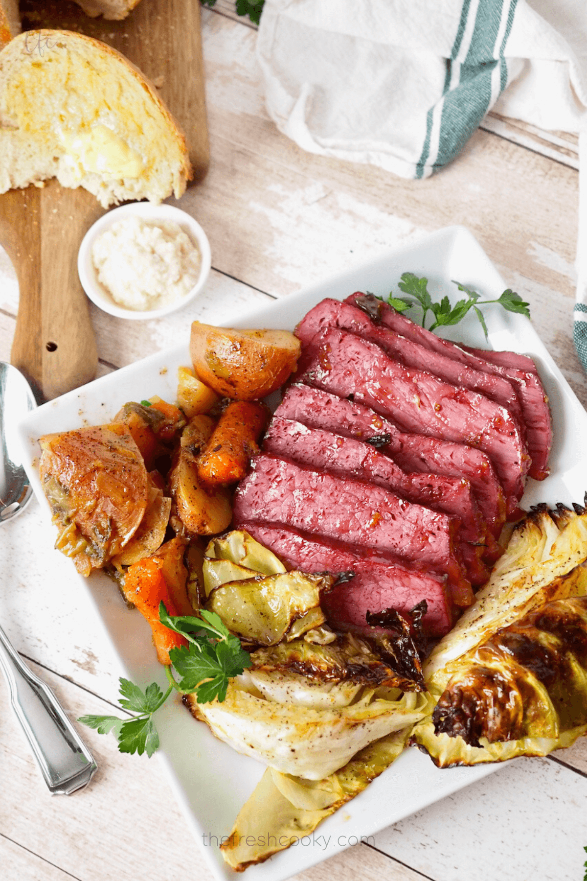 Easy and delicious baked corned beef recipe on platter with cabbage, potatoes and carrots.