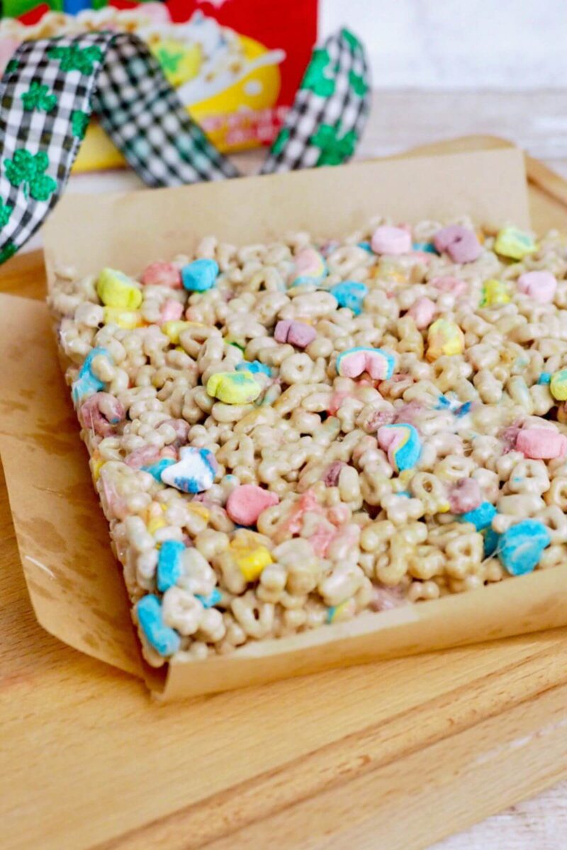 Using the parchment paper to easily lift the Lucky Charms treats out of the pan.