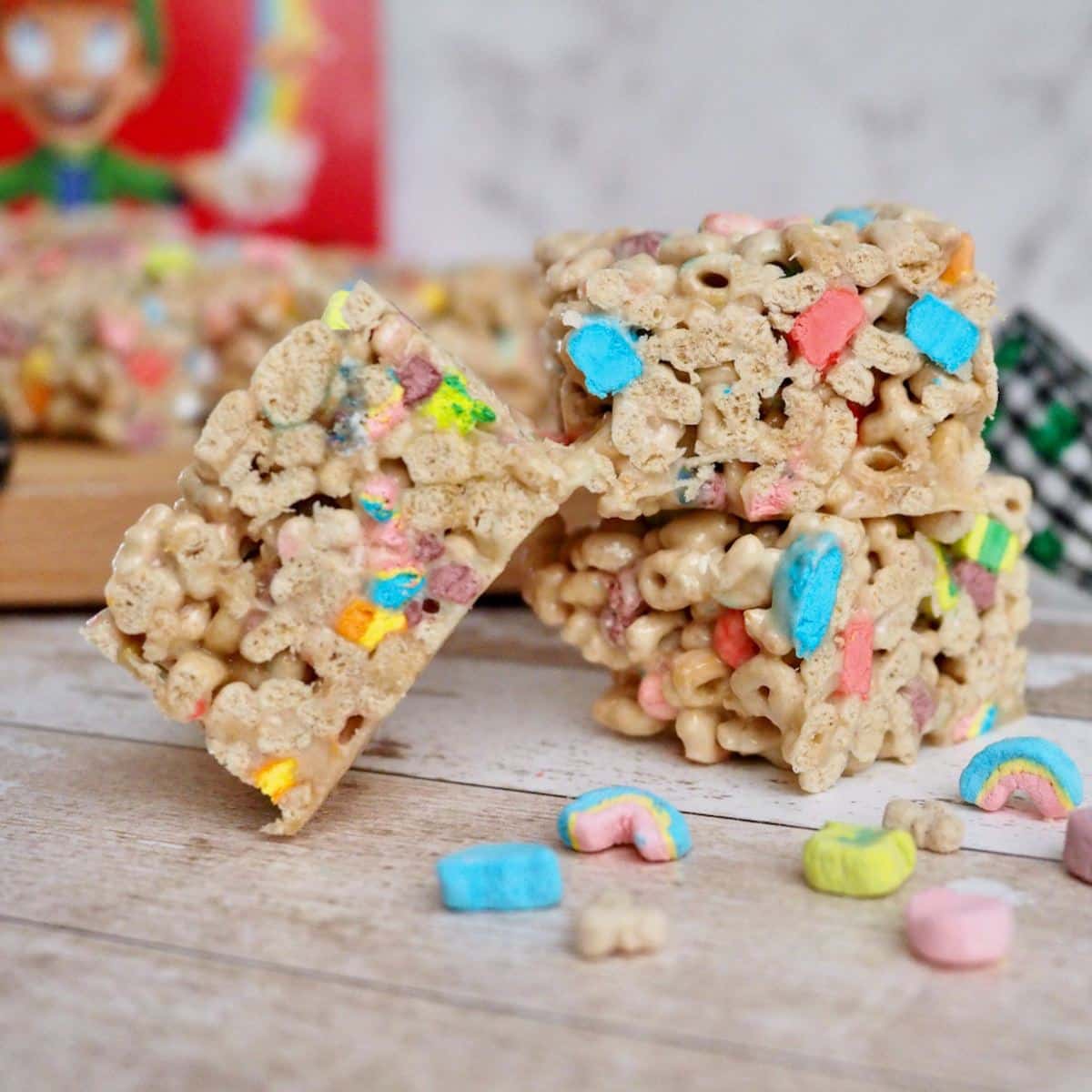 Lucky Charms treats squares stacked with extra Lucky Charms sprinkled around. 