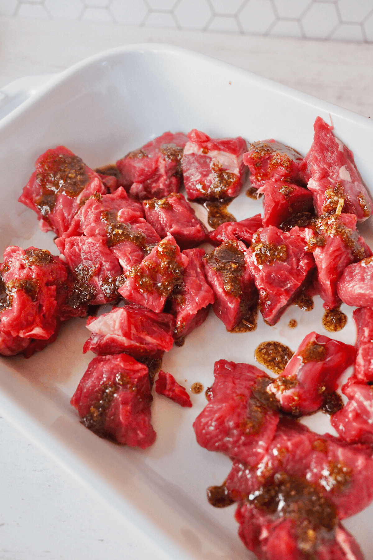 Marinade dribbled onto steak tips, ready to rub and coat.