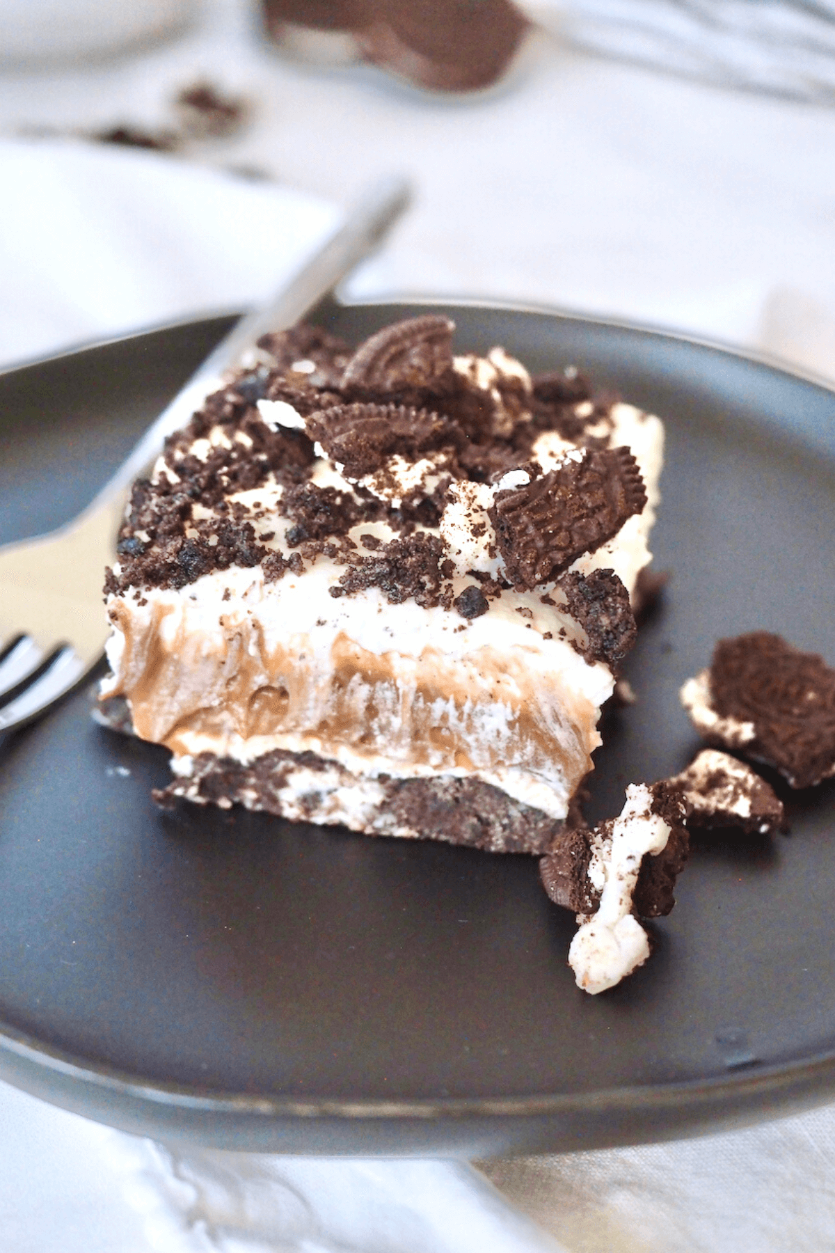 Oreo dessert square on a plate with crushed Oreos.