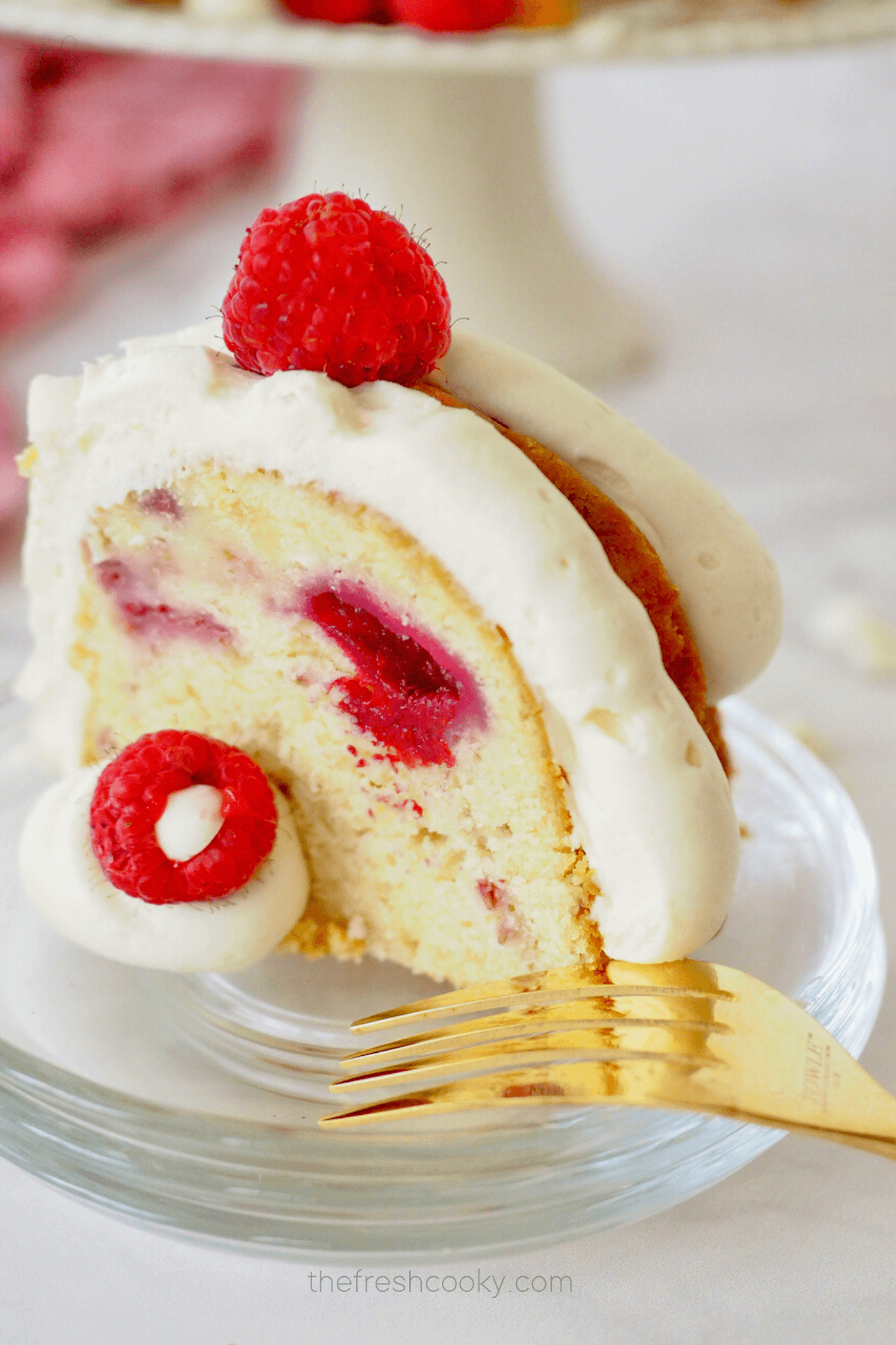 Slice of white chocolate bundt cake on glass plate with gold fork.