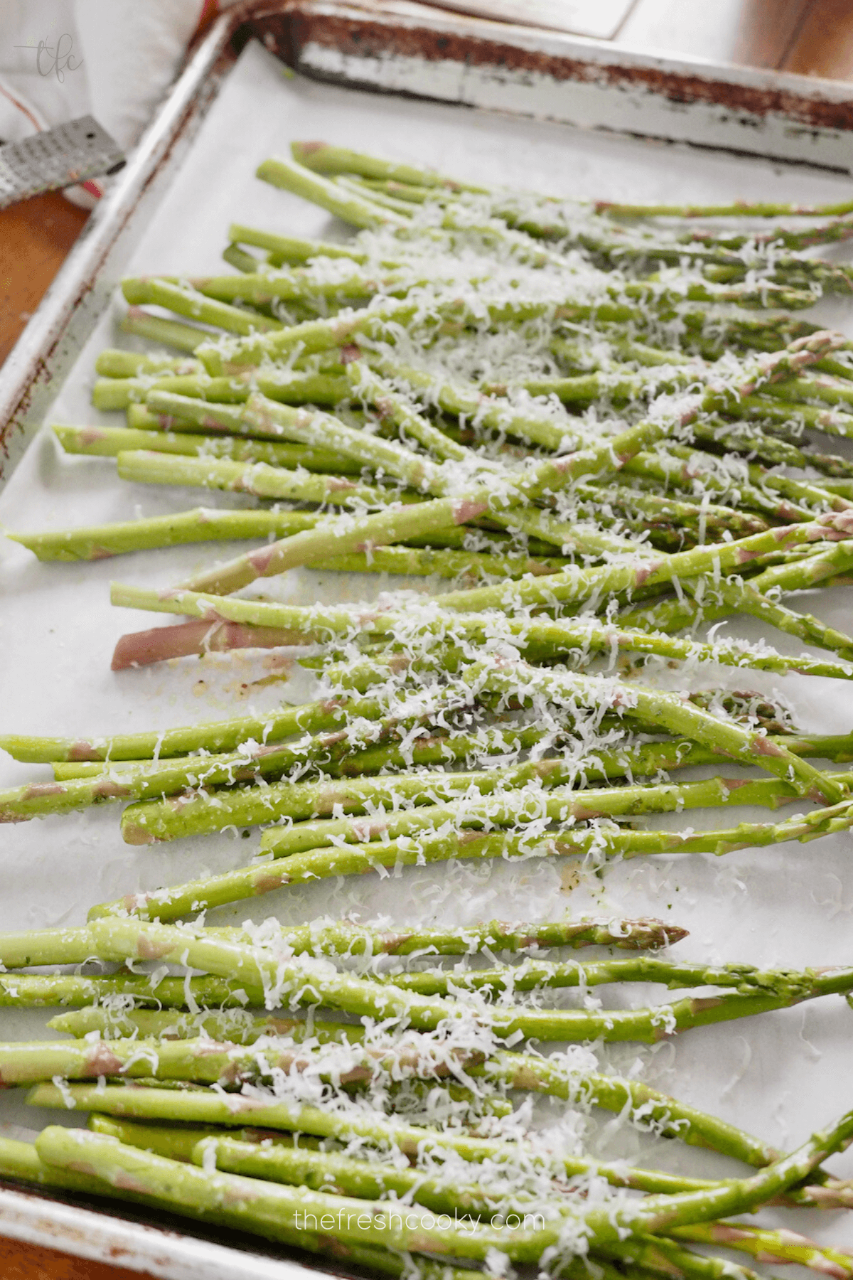 Air fryer asparagus ready for air fryer sprinkled with grated Parmesan cheese.