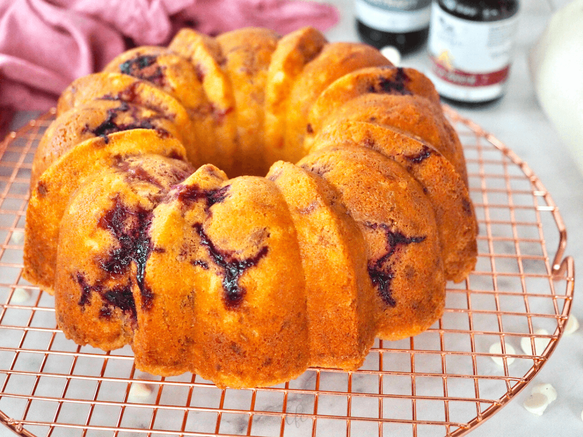 Unfrosted and cooling white chocolate raspberry bundt cake on cooling rack.