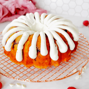 Square image of white chocolate raspberry bundt cake with copycat nothing bundt cake fingers of cream cheese frosting.