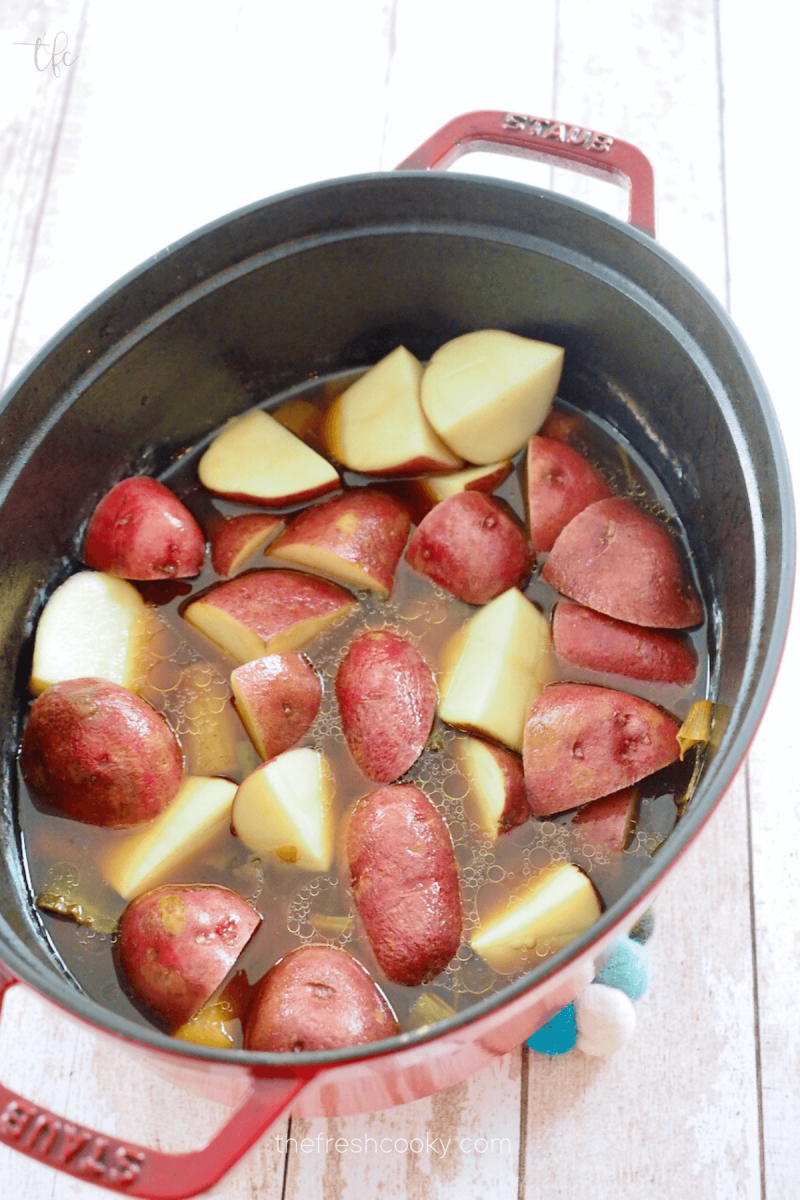 Quartered potatoes in pot with carrots and beer to cook for corned beef recipe. 