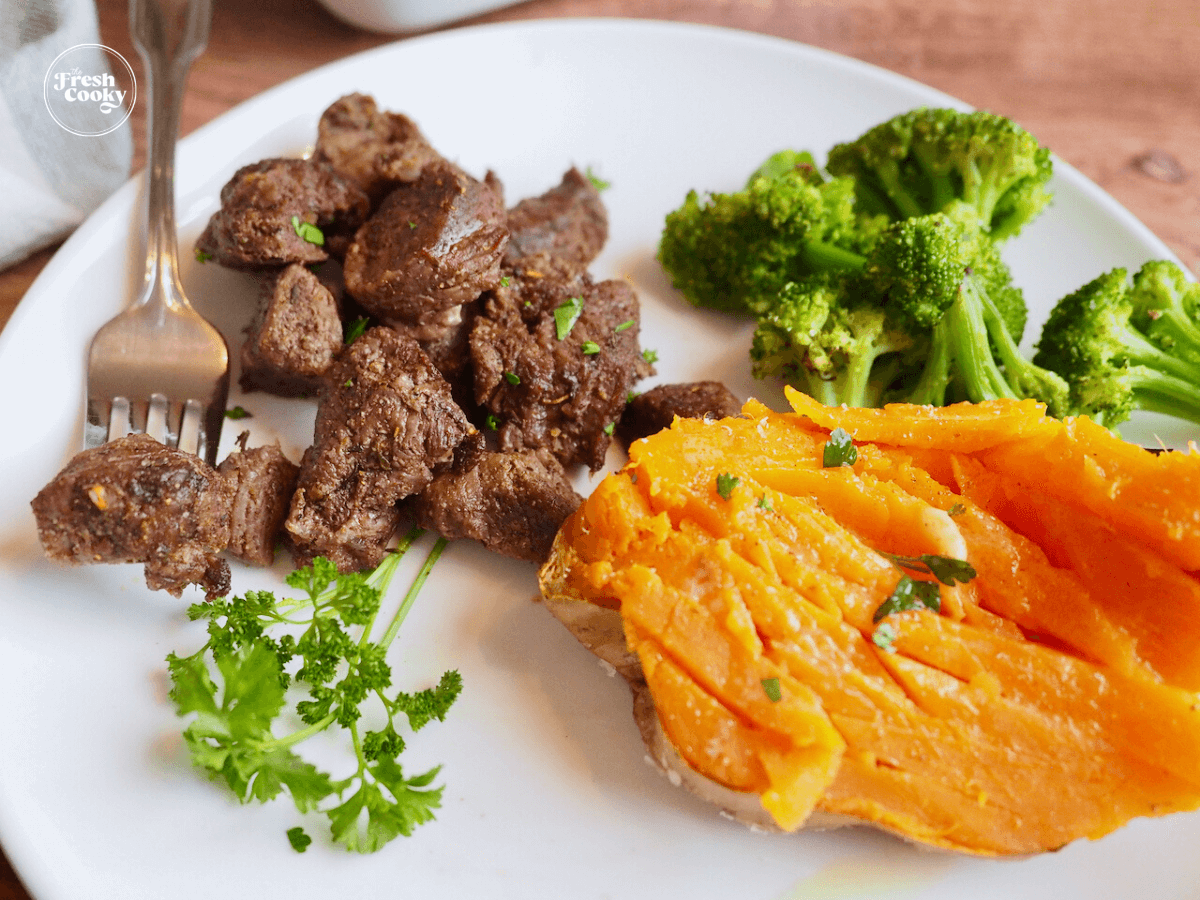Air Fryer Steak Tips on plate with fork and sweet potato and broccoli.