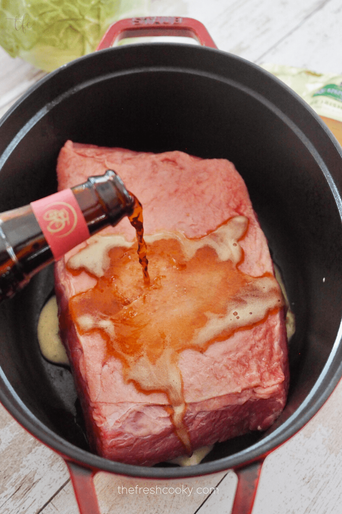 Pouring beer on top of corned beef in dutch oven. 