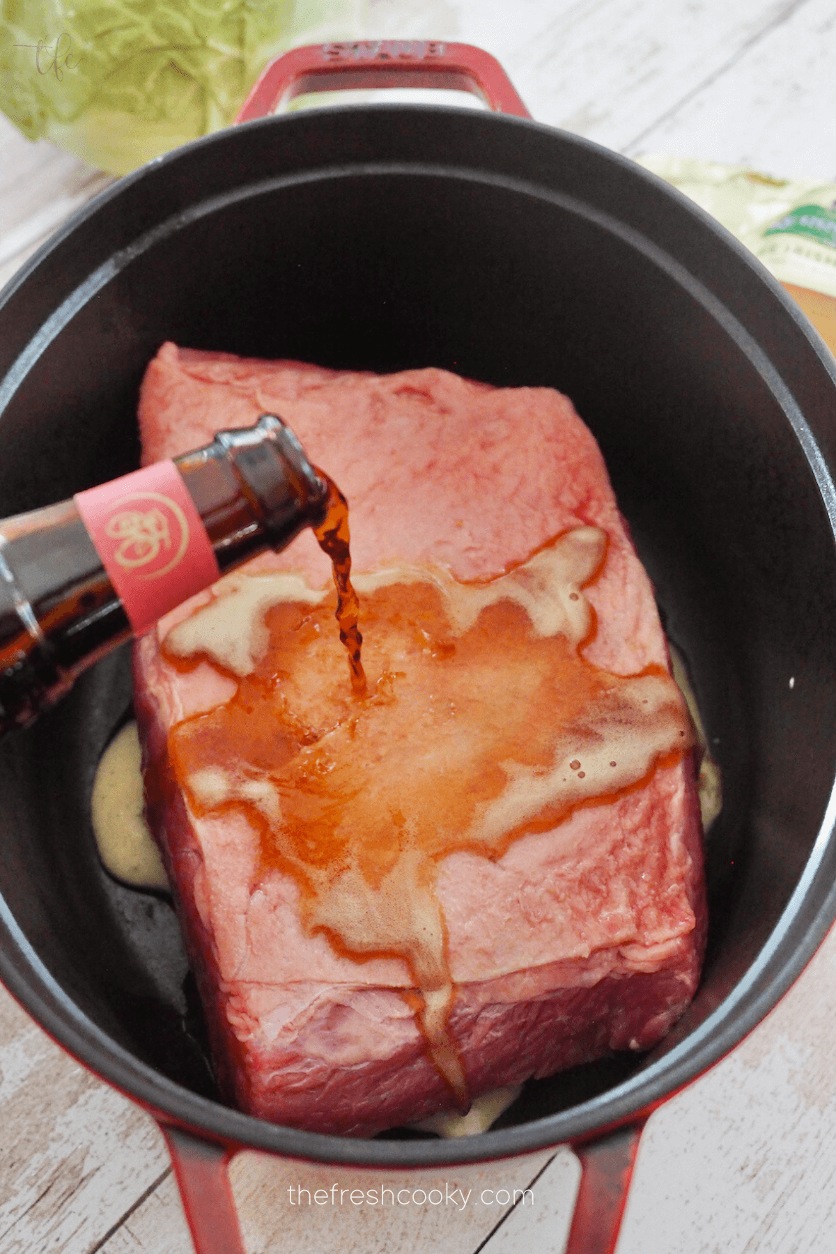 Pouring beer on top of corned beef in dutch oven.