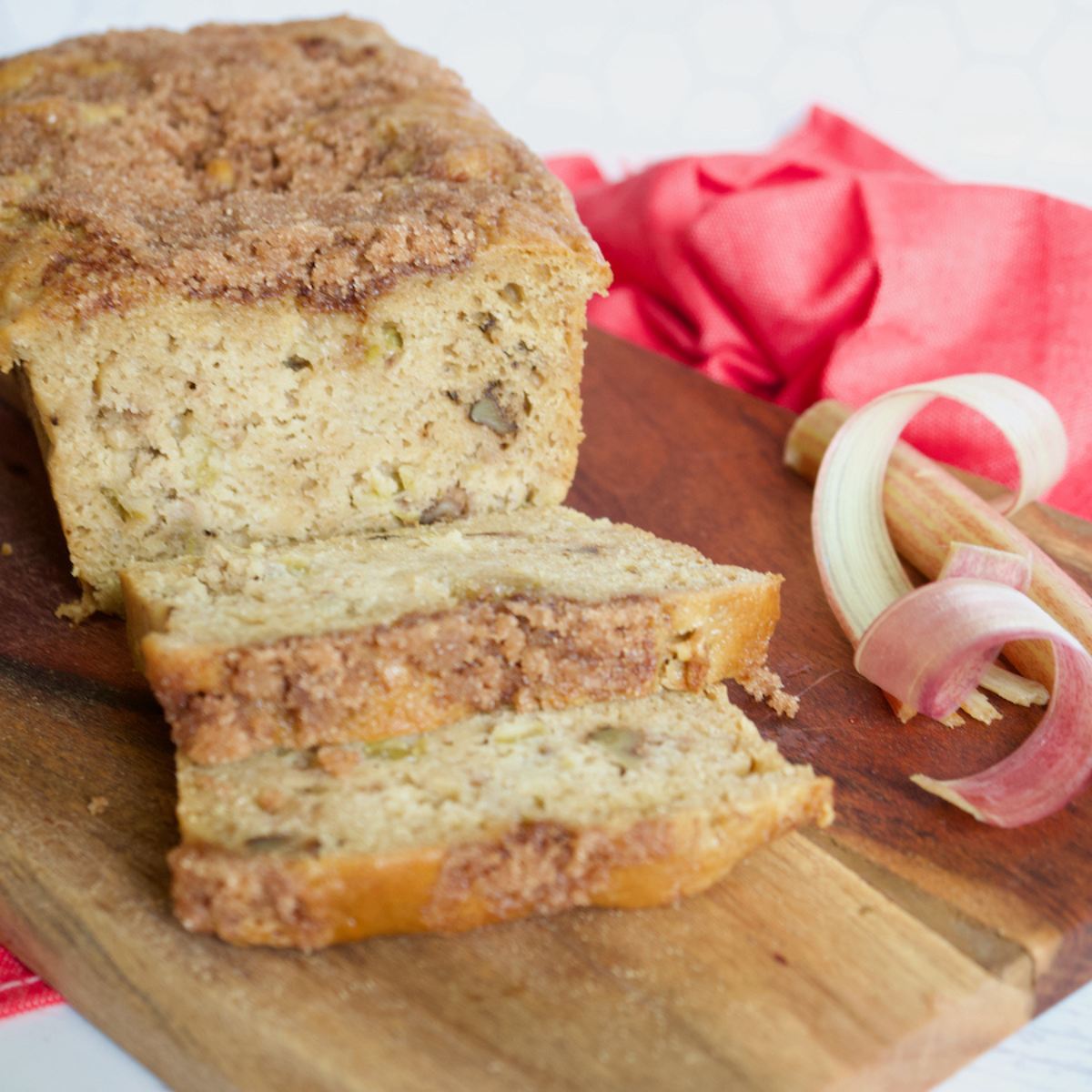 A loaf of rhubarb bread on cutting board with a few slices.