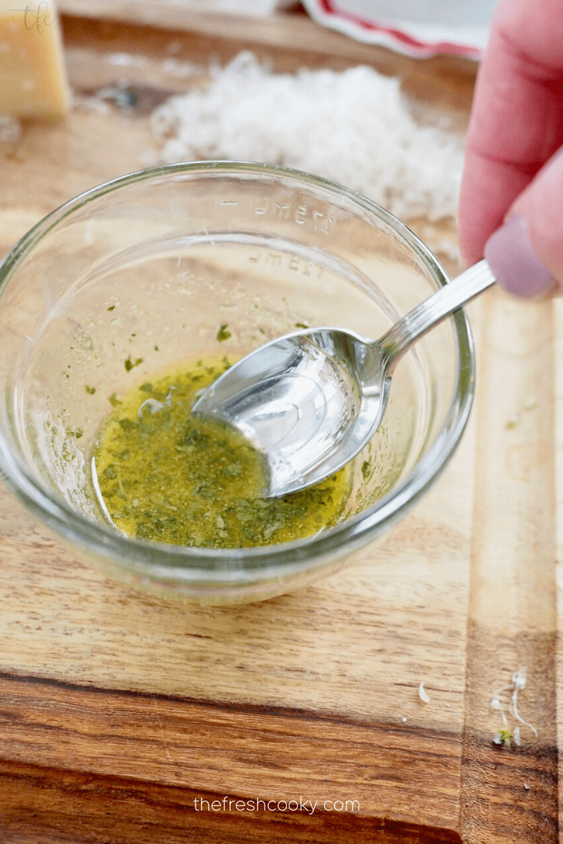 Spoon mixing oil, spices for air fryer asparagus .