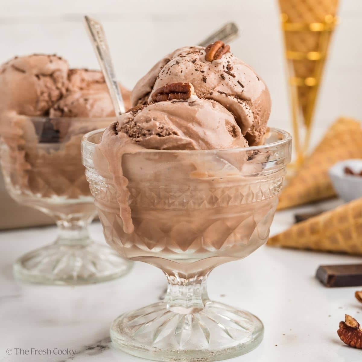 Scoops of creamy chocolate ice cream in glass footed bowls.