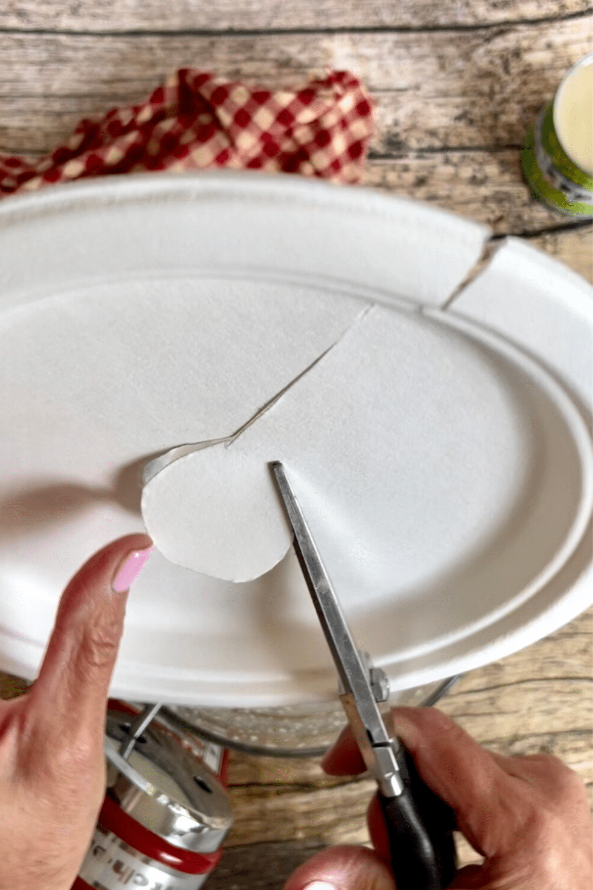 Cutting hole out of paper plate to be whipping cream splatter shield. 