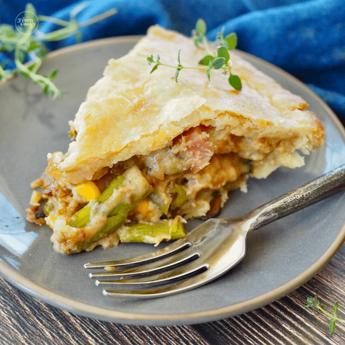 Slice of ham pot pie on a plate with fresh thyme.