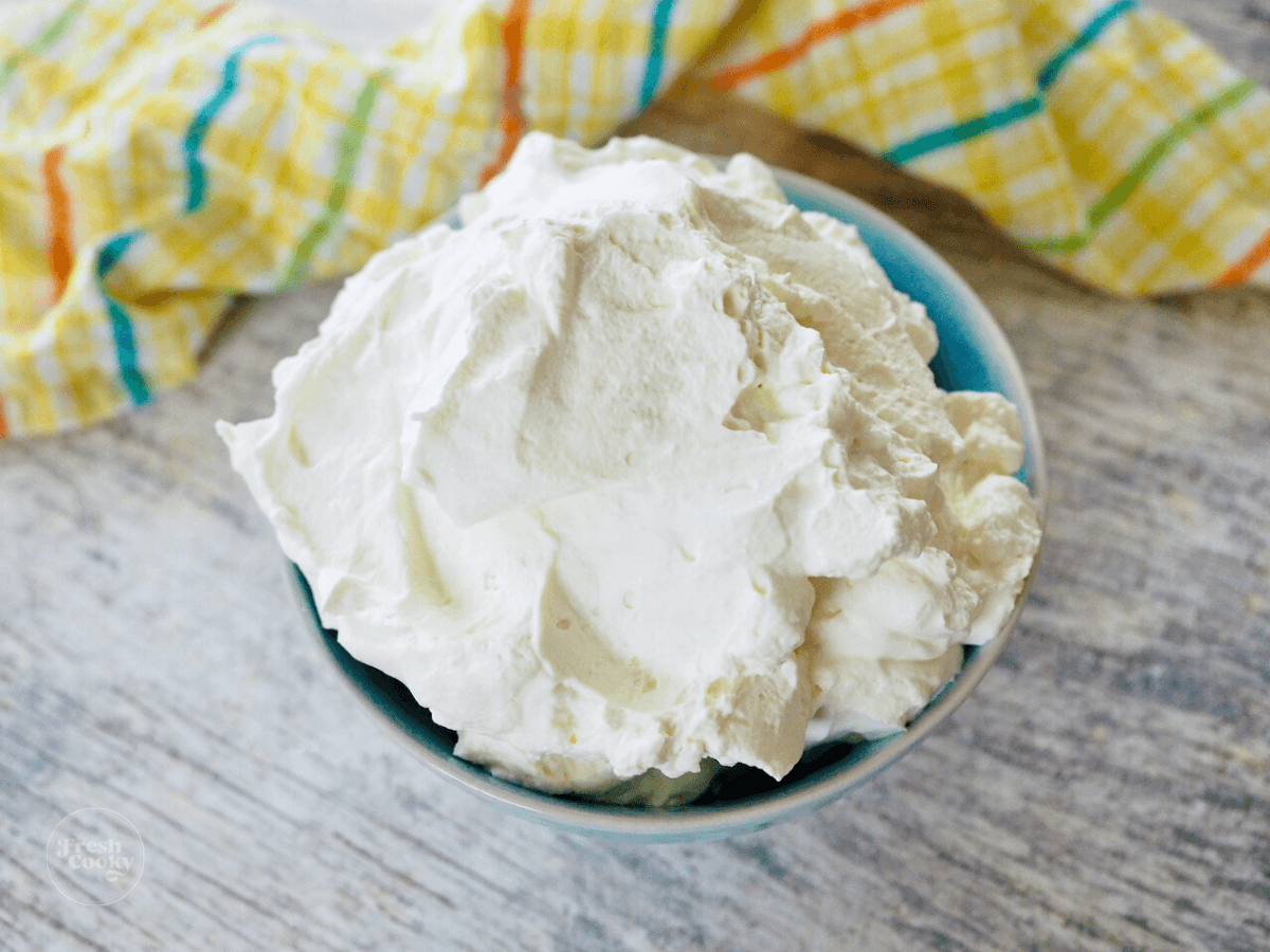 Homemade Cool whip in bowl with yellow tea towel.