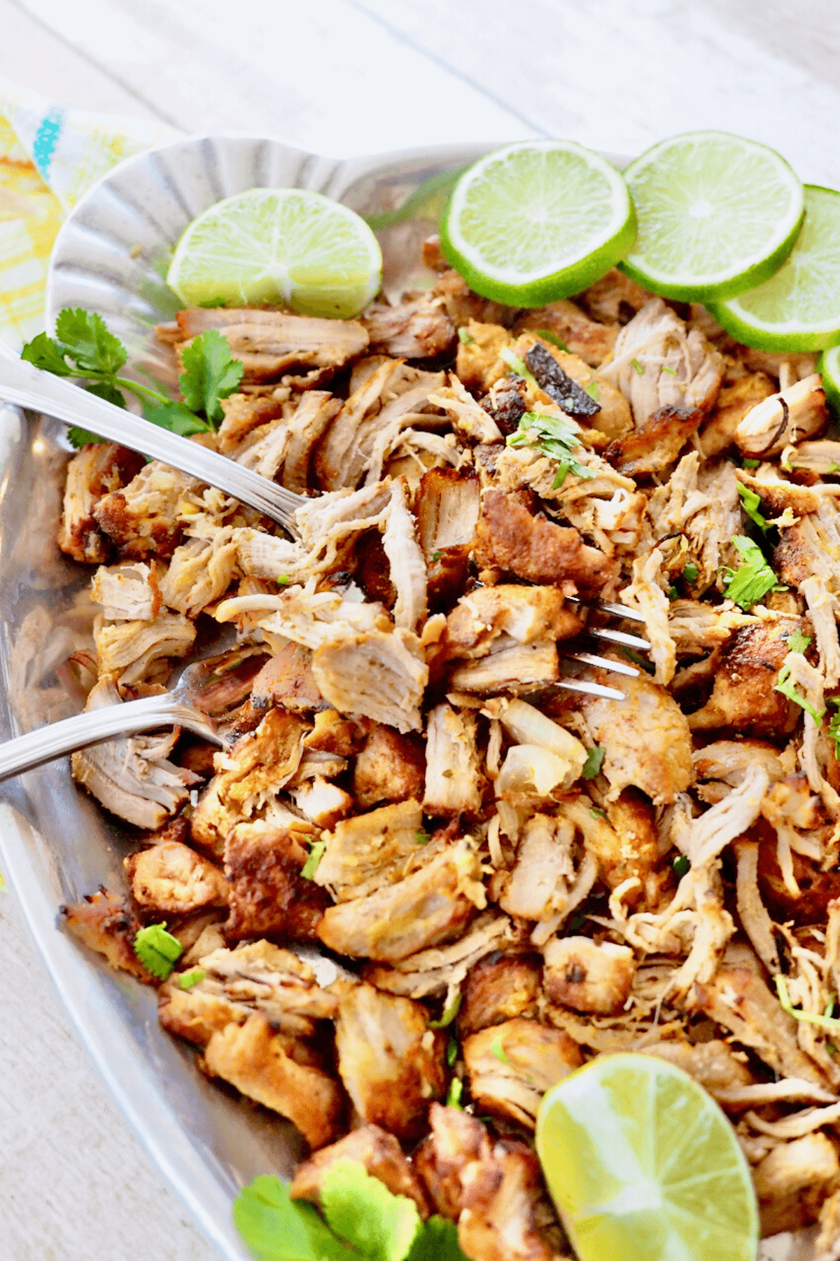 Instant Pot Carnitas on platter with limes and fresh cilantro.