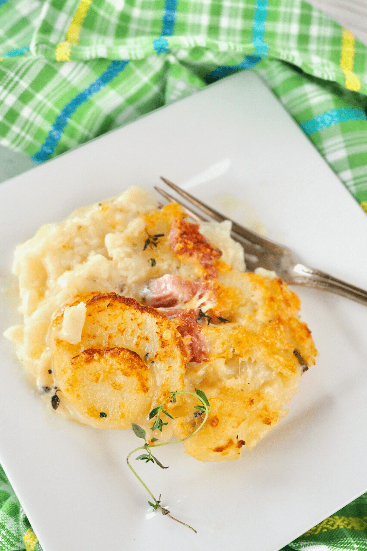 Plate of Instant Pot Scalloped potatoes with ham on a plate with fresh thyme.