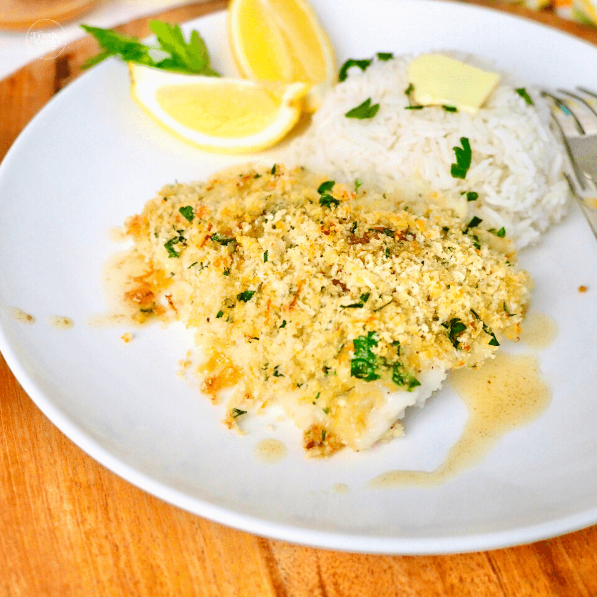 Panko Parmesan Baked Cod recipe plated with a drizzle of lemon garlic butter and a mound of fragrant basmati rice.