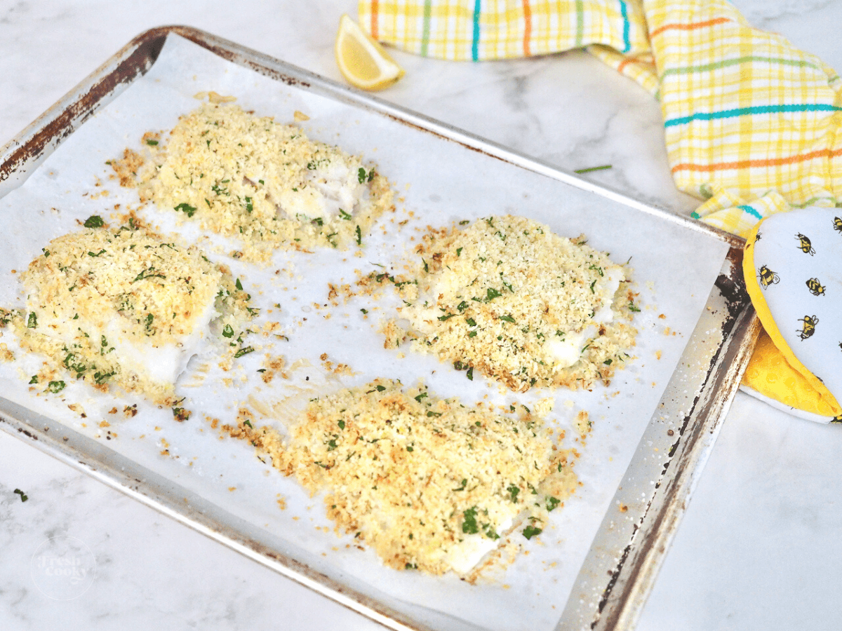 Crispy and crunchy panko parmesan crusted baked cod on parchment lined baking sheet.