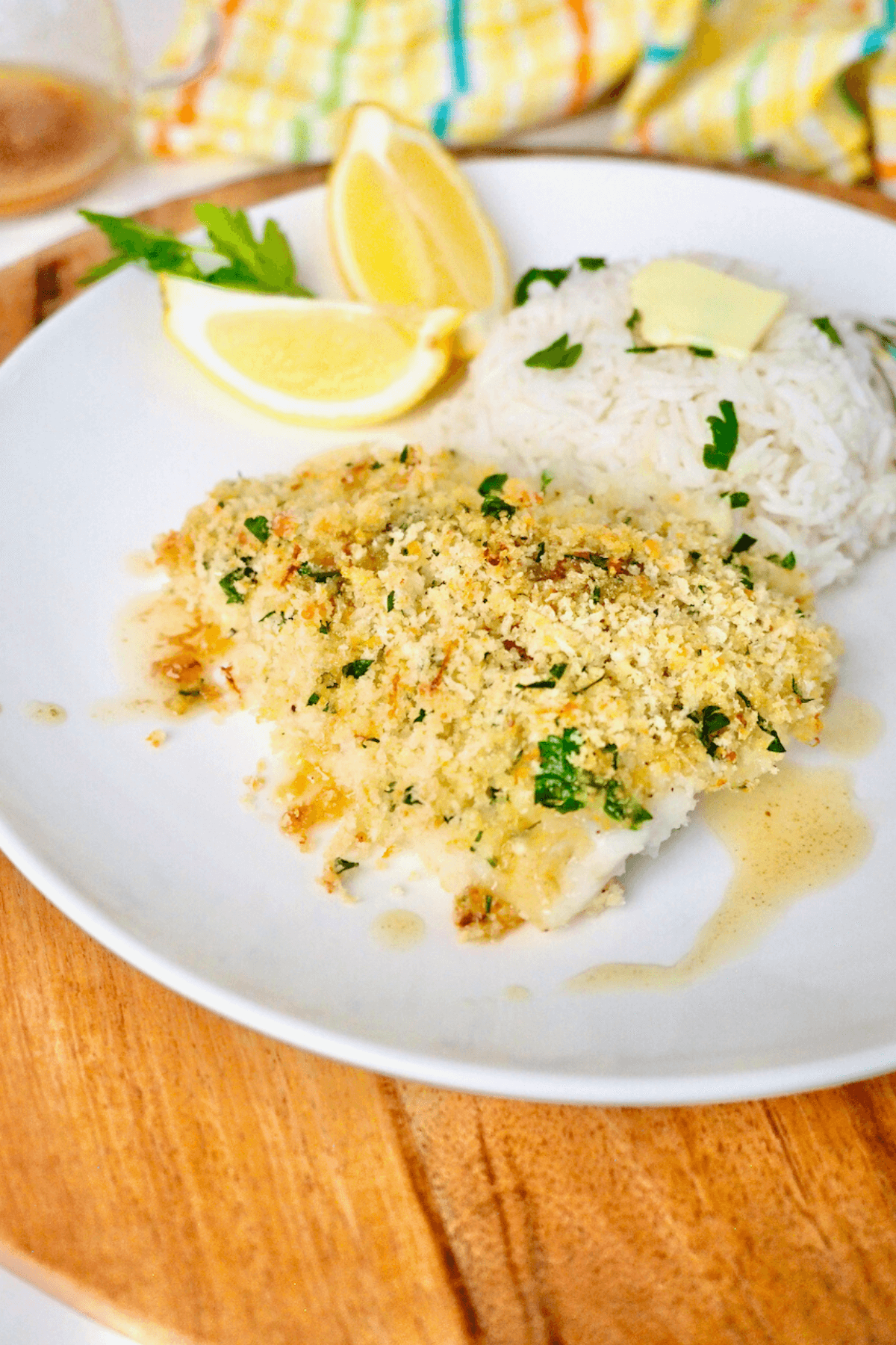 Panko Parmesan Baked Cod recipe with lemon butter sauce on a plate with rice and lemon.