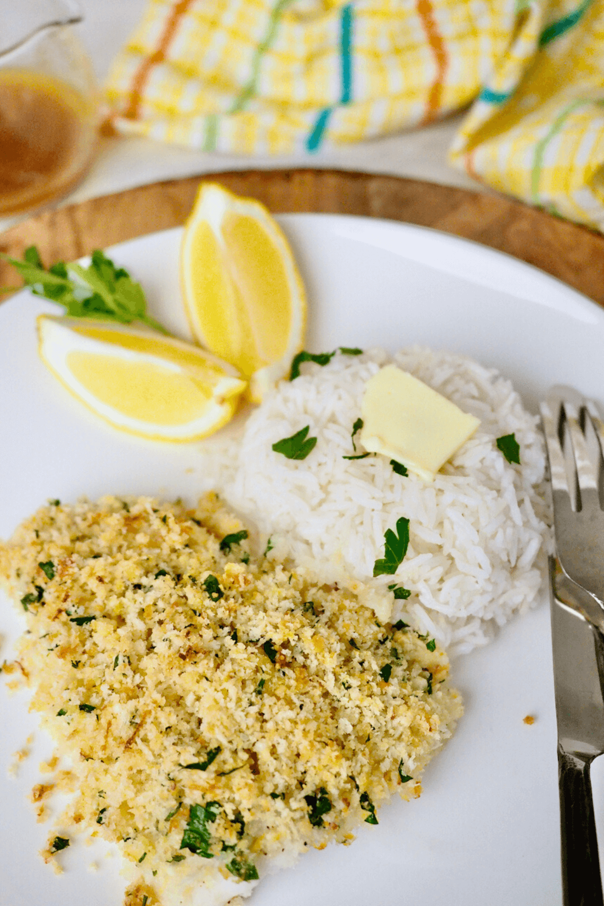 Parmesan panko baked cod recipe on plate with white rice and lemon wedges.