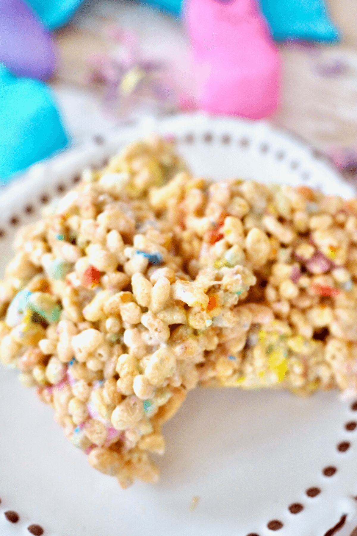 Egg plate with three squares of Peeps Rice Krispie Treats with colorful peeps marshmallows behind.