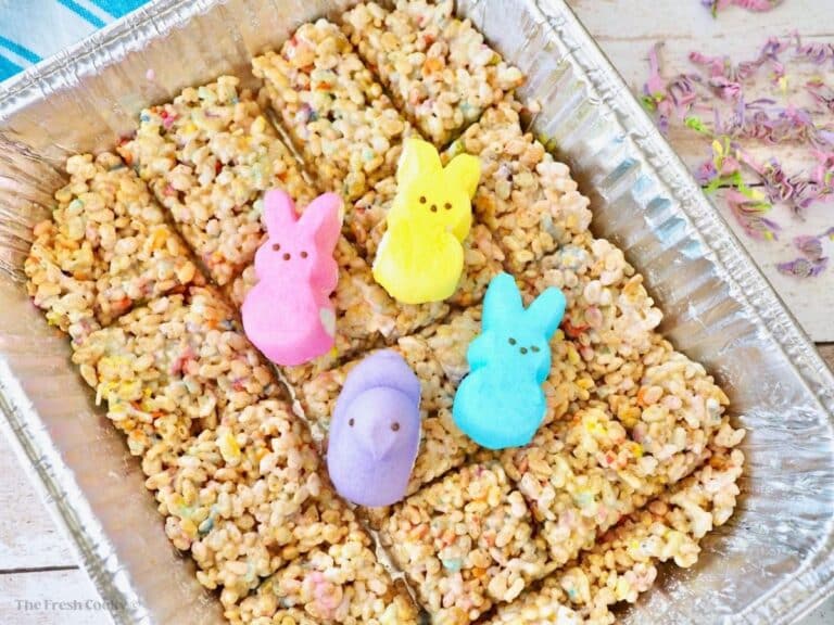 Foil pan filled with sliced Peeps rice krispie treats topped with four Peeps marshmallow bunnies and ducks in pink, yellow, blue and purple.