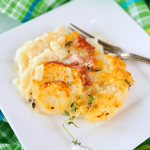 Instant Pot Scalloped Potatoes serving on a square plate with fresh thyme and ham.