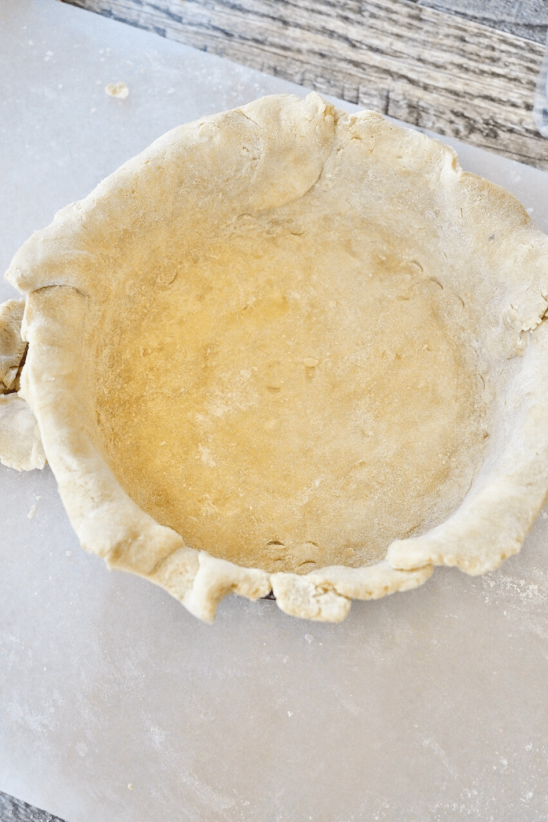 Pressing the pizza rustica dough crust into the pan, with a little overhang. 