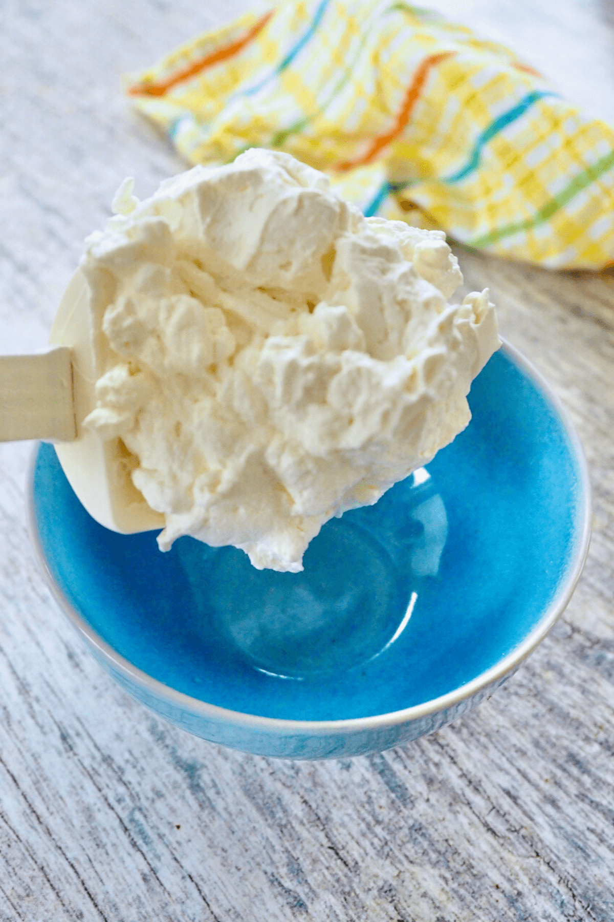 Spooning homemade whipped cream into blue bowl.
