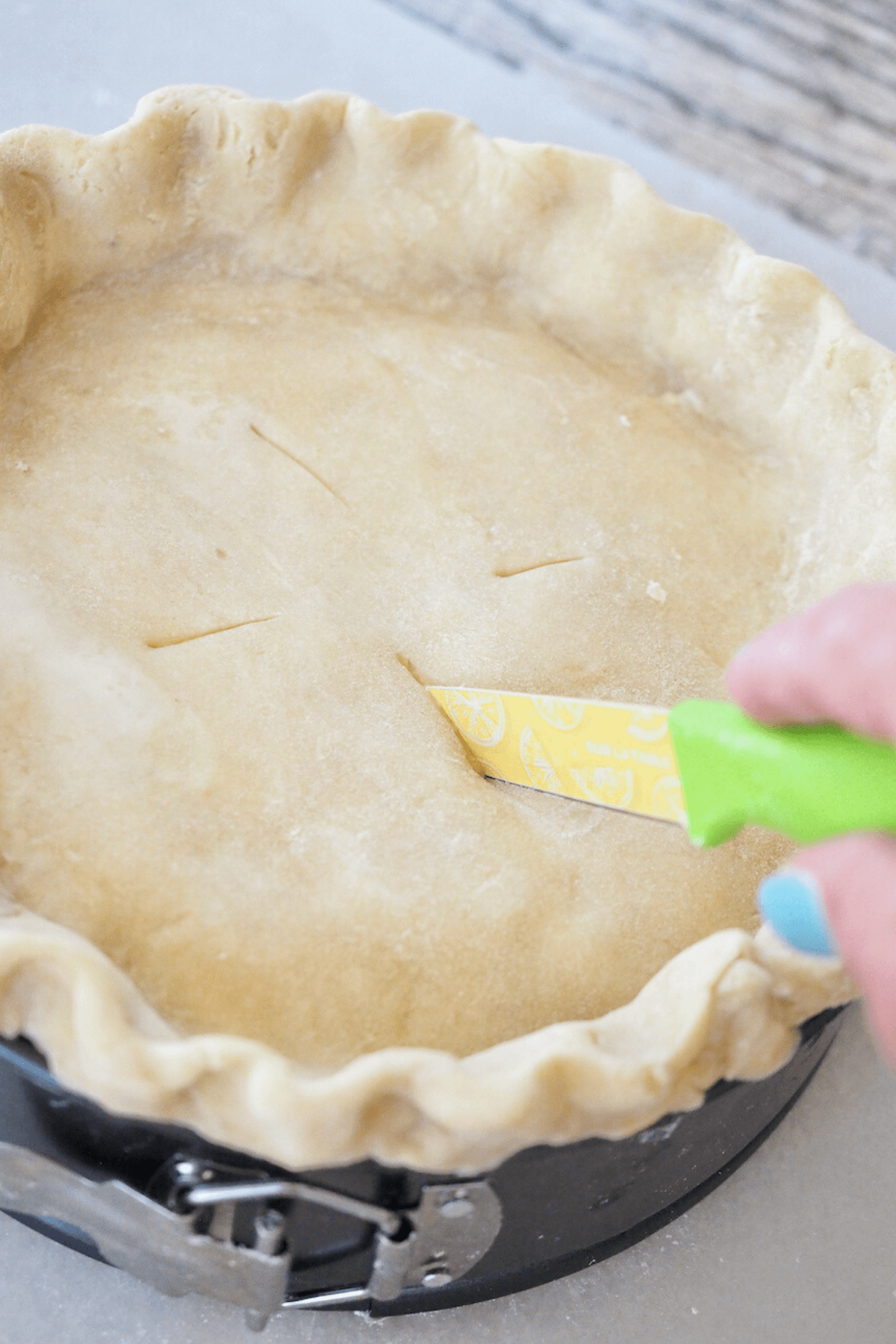Cutting slits into crust to allow steam escape.
