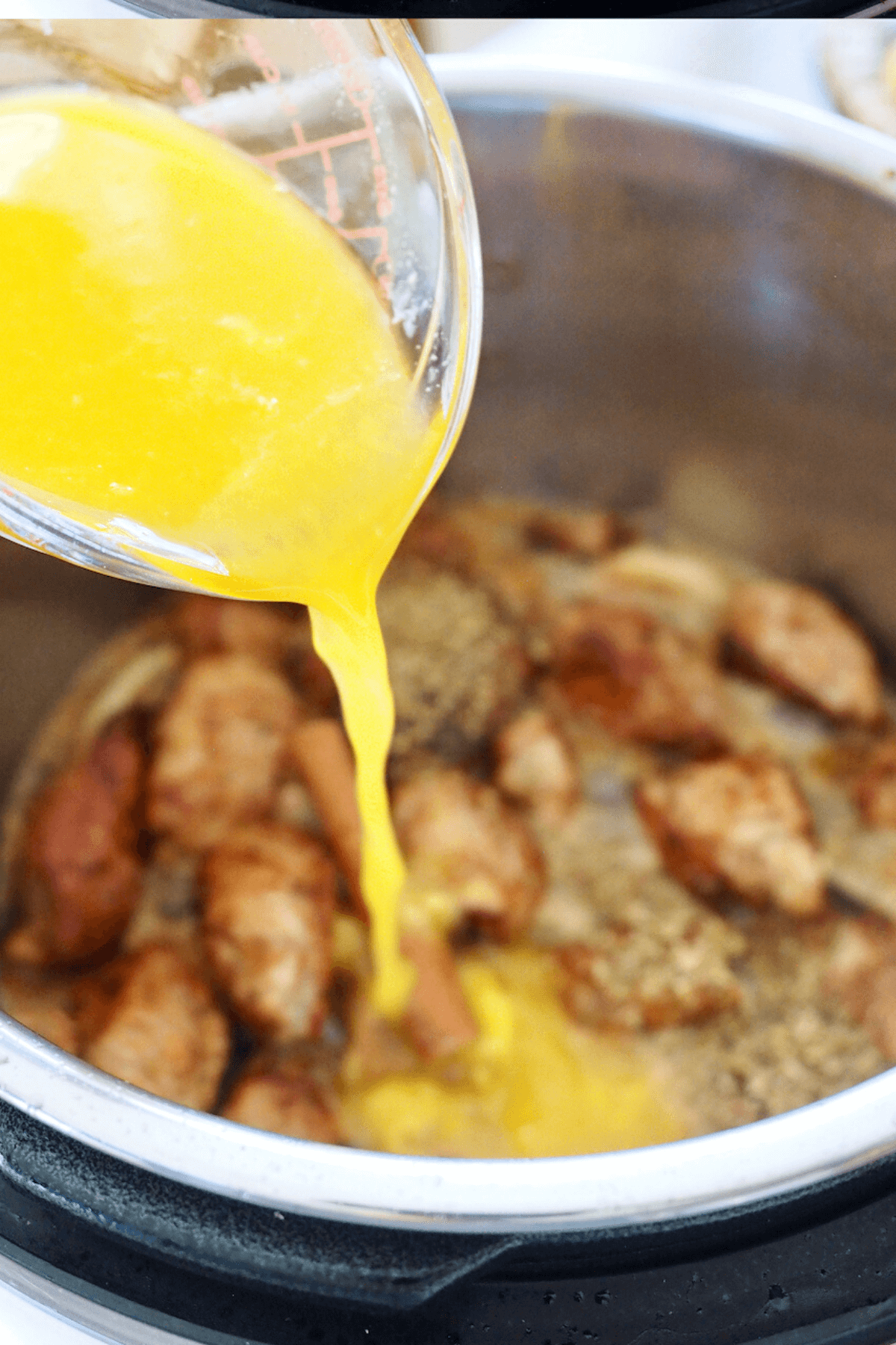 Pouring in fresh squeezed orange juice to pork carnitas.
