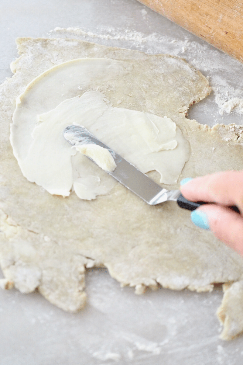 Spreading butter onto rolled out leftover pie dough. 