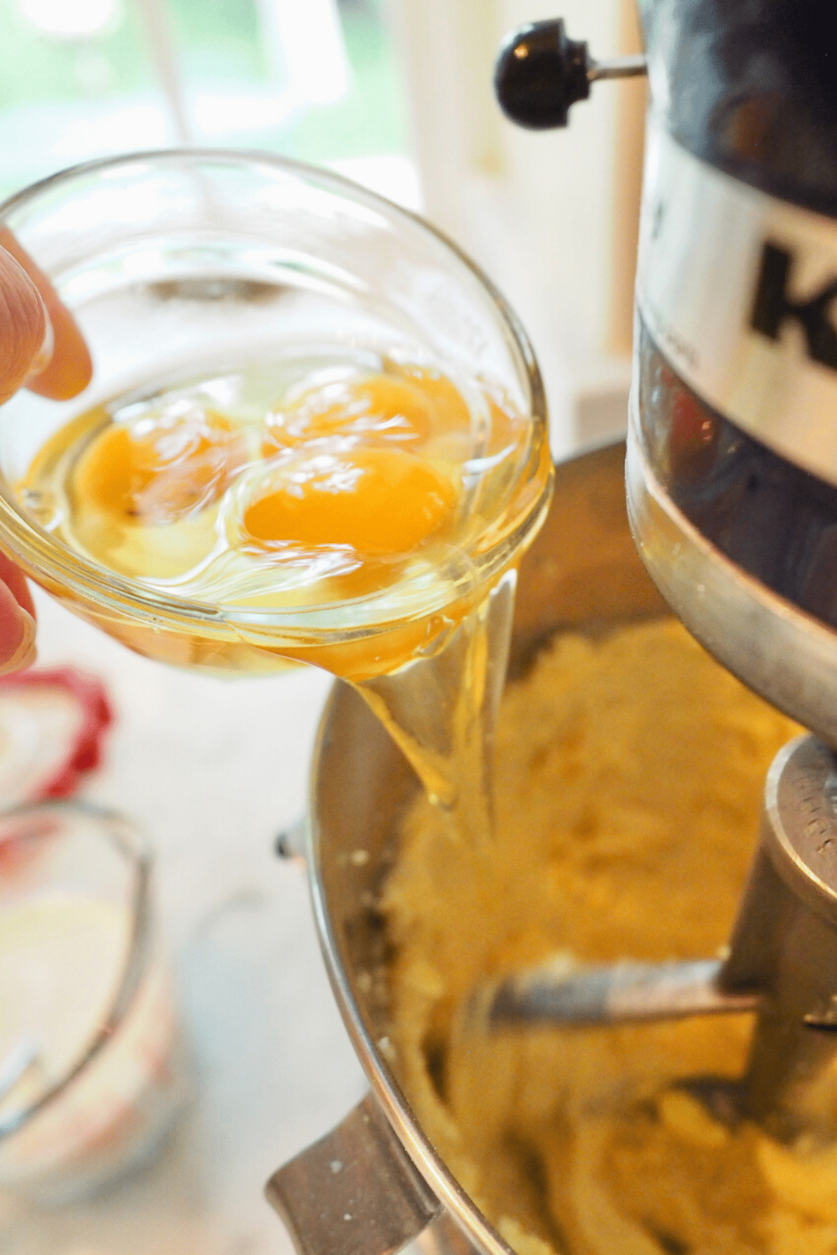 Adding eggs into the batter for lemon bundt cake. 