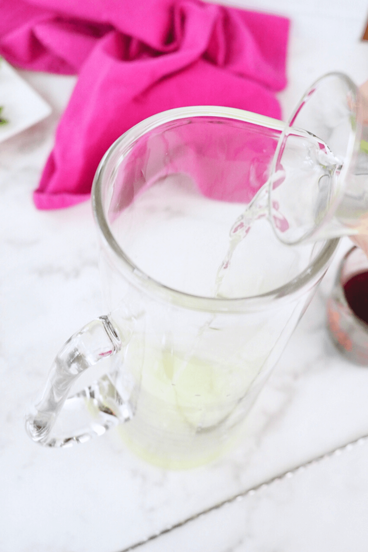Pouring in lemon vodka into pitcher. 