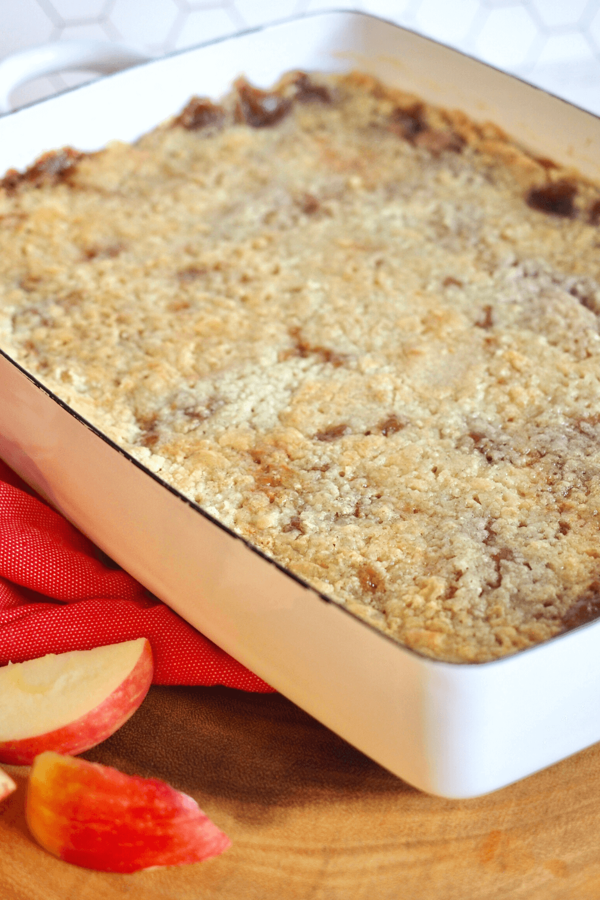 Caramel Apple Dump Cake in pretty white pan with apple slices nearby.